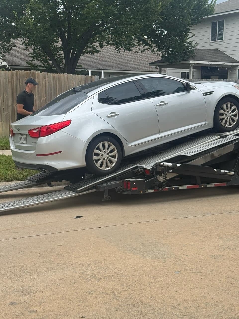 Silver 2014 Kia Optima sedan being loaded onto an open auto transport carrier in Houston, TX