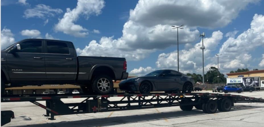 Toyota GR86 sports car loaded on an open auto transport carrier
