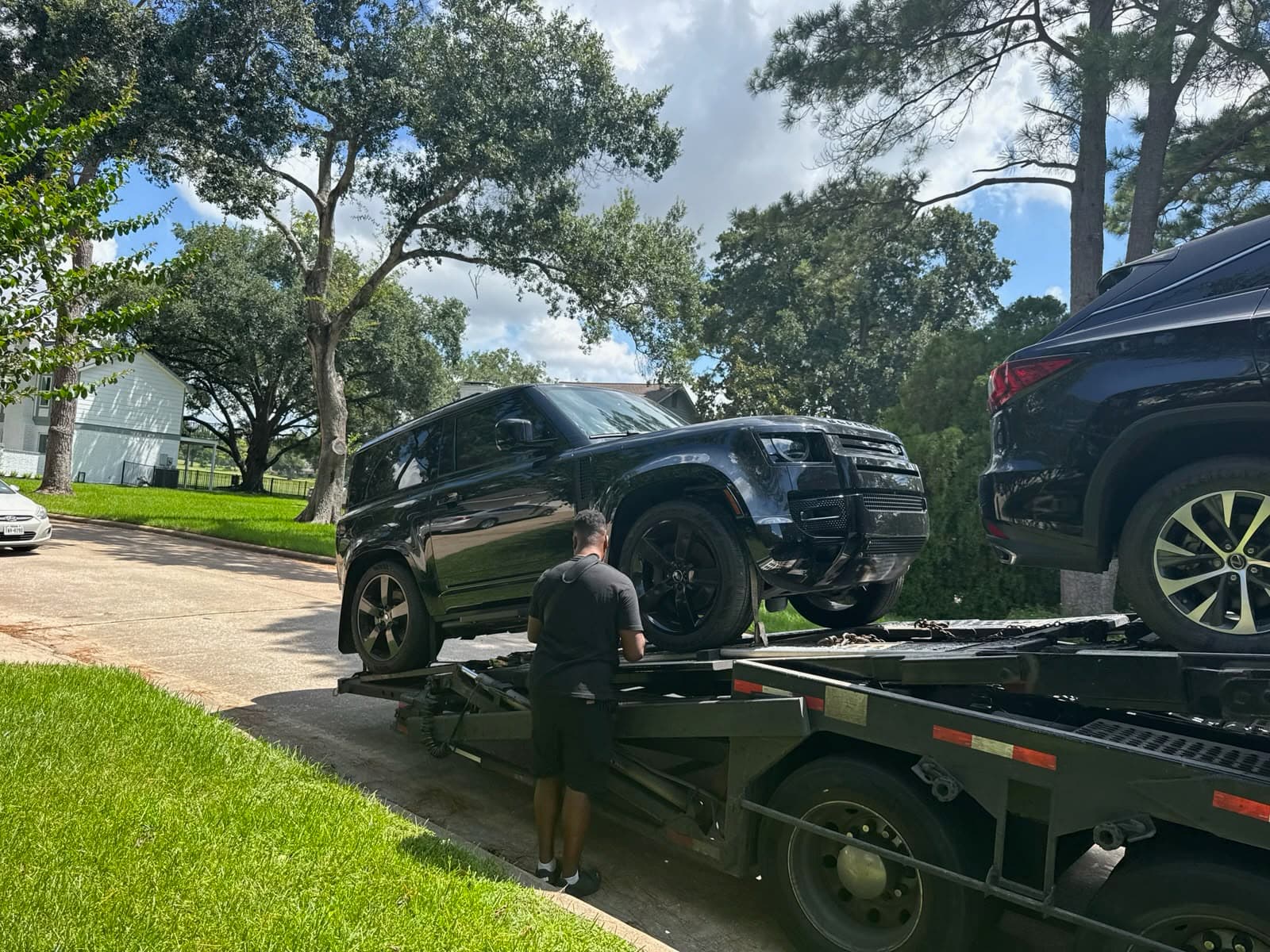 Land Rover Defender 90 being loaded onto an open auto transport carrier in Houston, TX