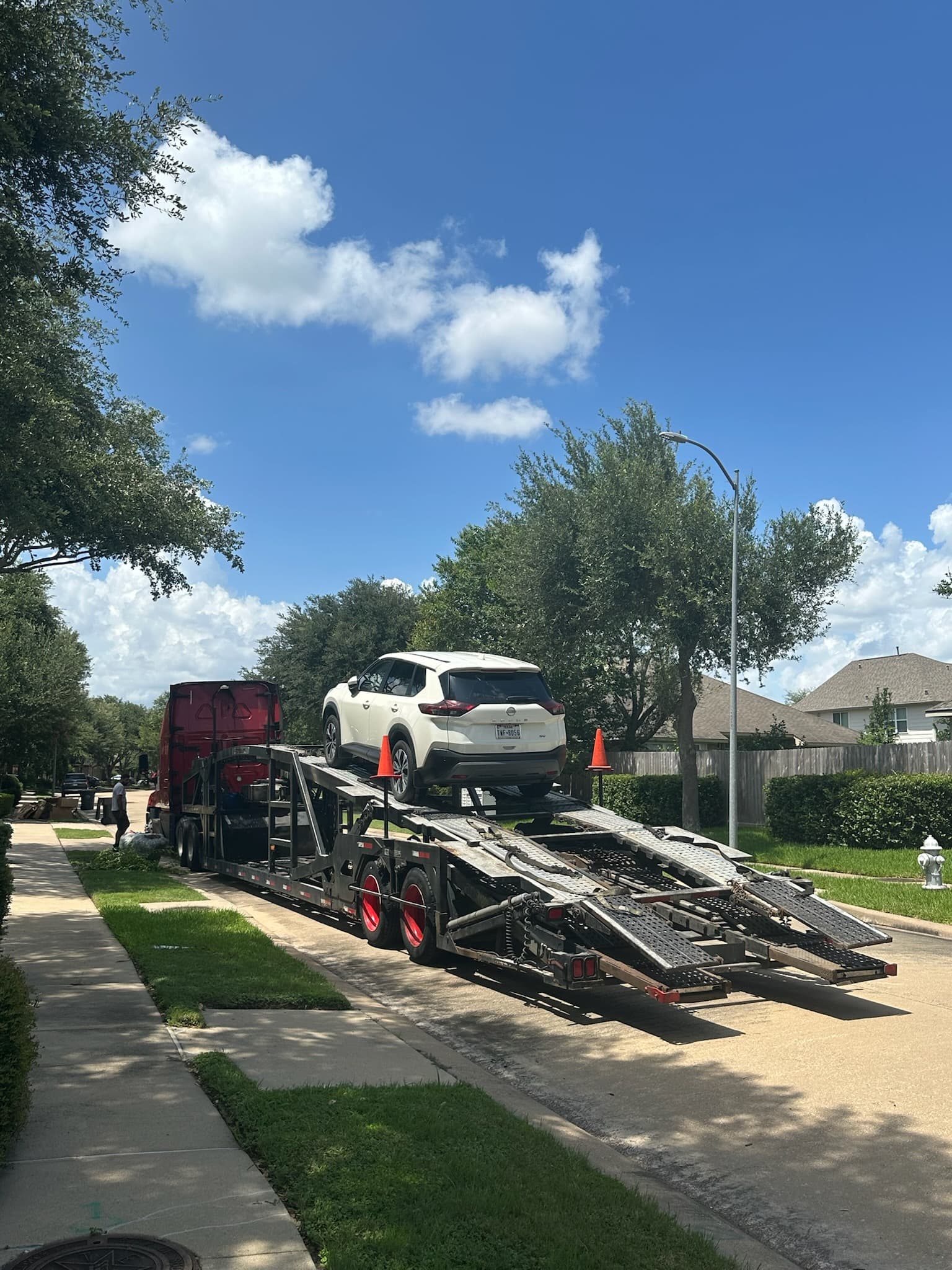 White Nissan Rogue loaded on an open auto transport carrier in Sugar Land, TX