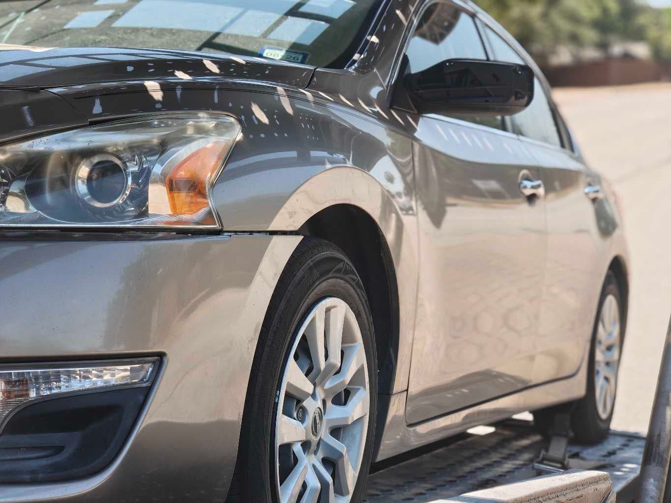 Close-up of the Nissan Altima's wheel and fender secured on the open carrier