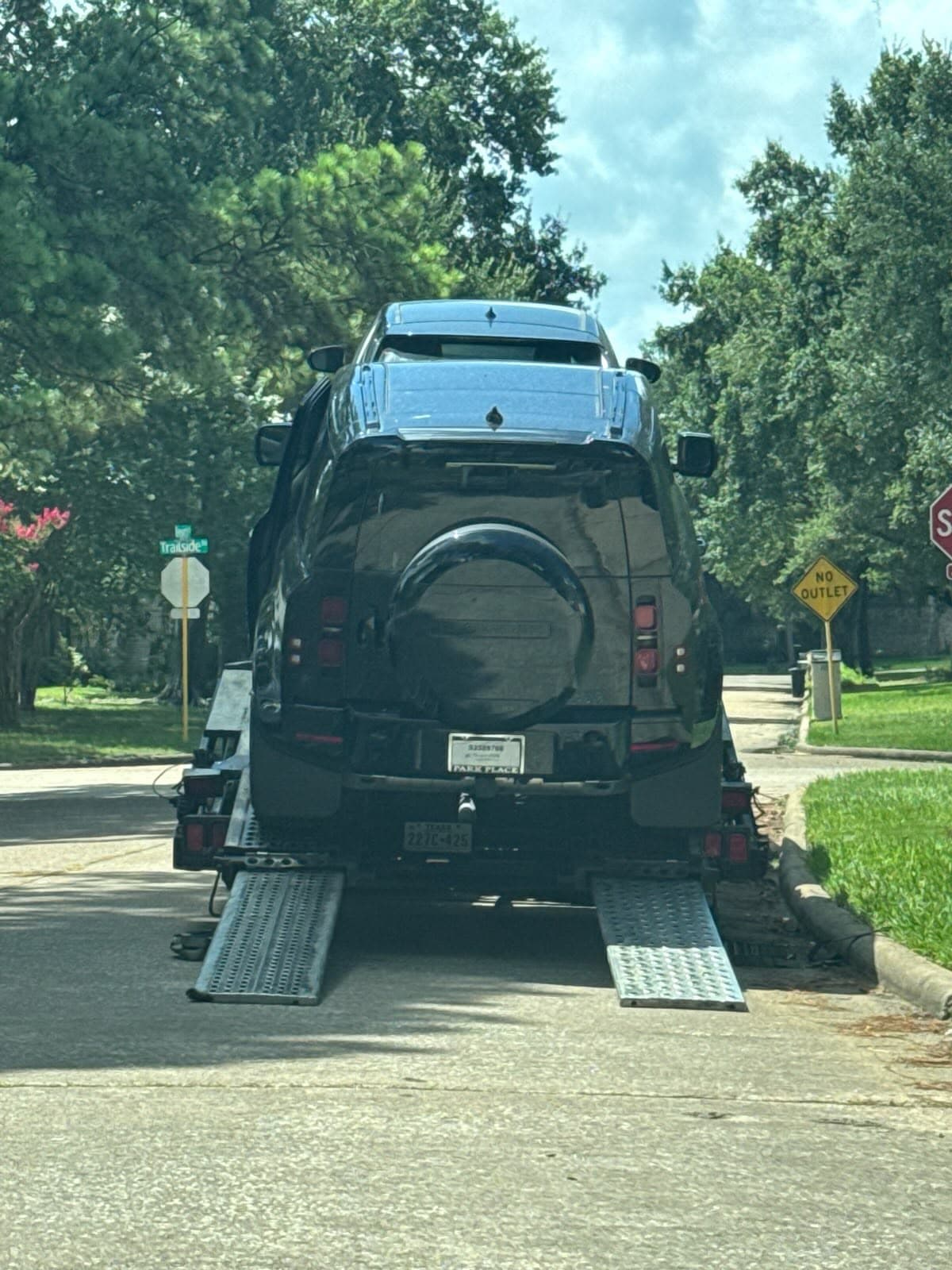 Black Land Rover Defender 90 loaded on an open auto transport carrier in Houston, TX