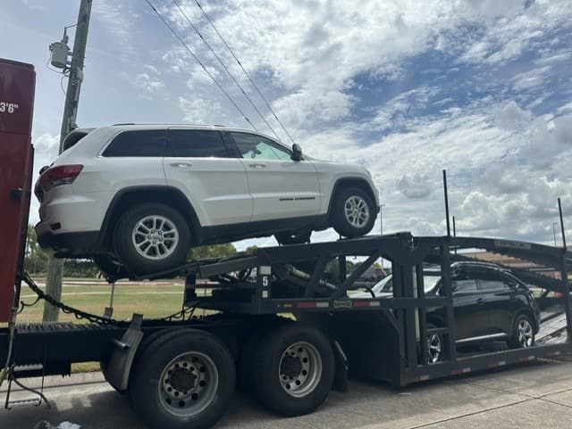 Jeep Grand Cherokee loaded on an open auto transport carrier in Katy, TX