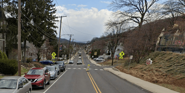 Two-way residential street near Reading, PA with parked cars narrowing the road and limited space for a large transport truck