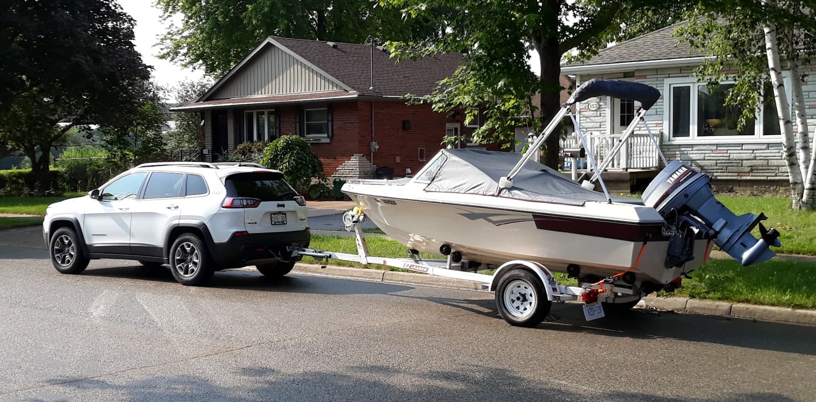 SUV towing a powerboat on a trailer down a residential street