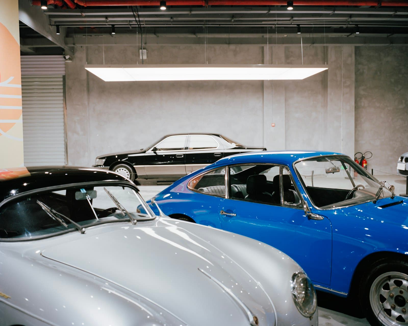 Classic Porsche 356 and 911 collector cars parked together in a modern climate-controlled garage
