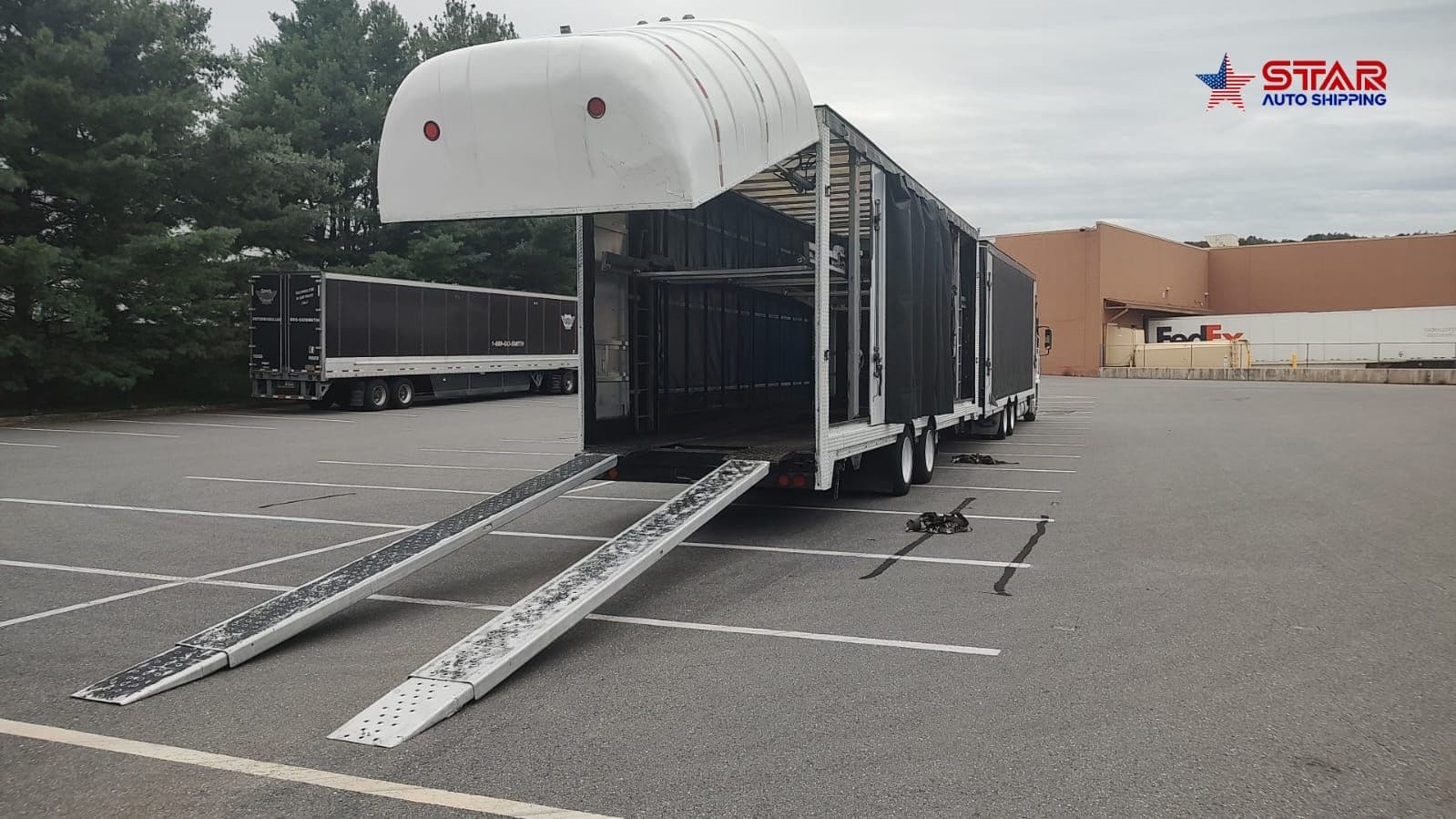 An enclosed auto transport trailer with its ramps lowered, ready to load a vehicle