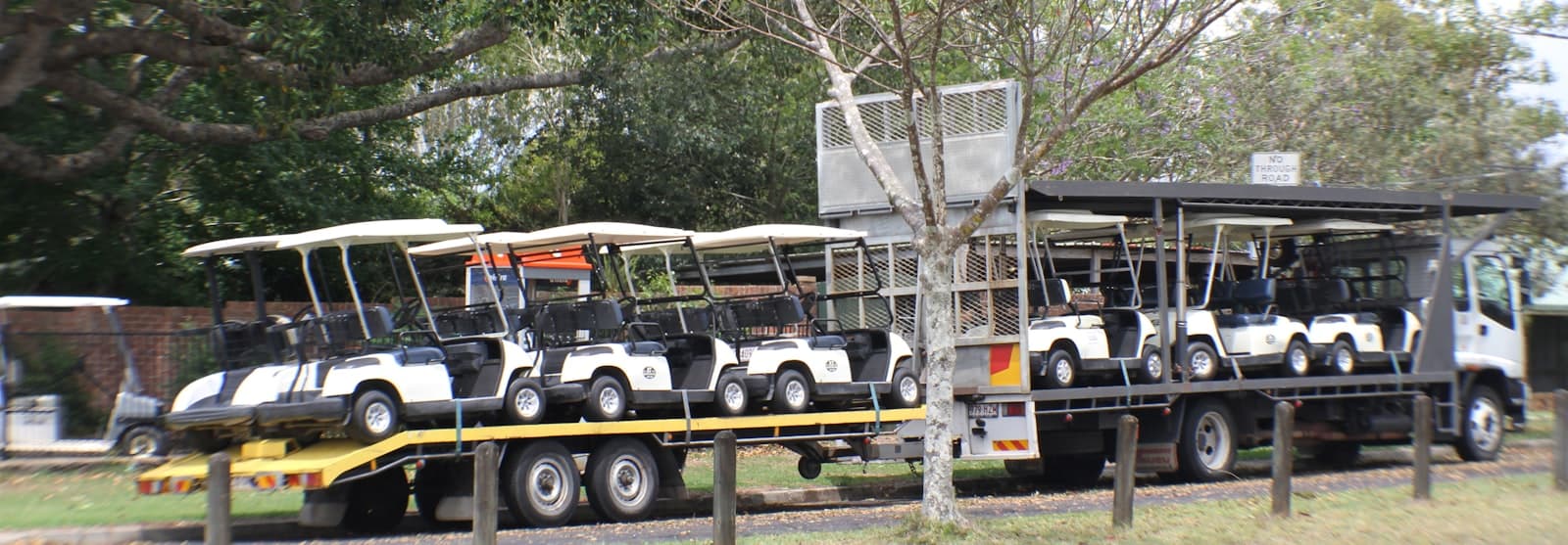 Golf carts loaded and secured on an open flatbed transport trailer