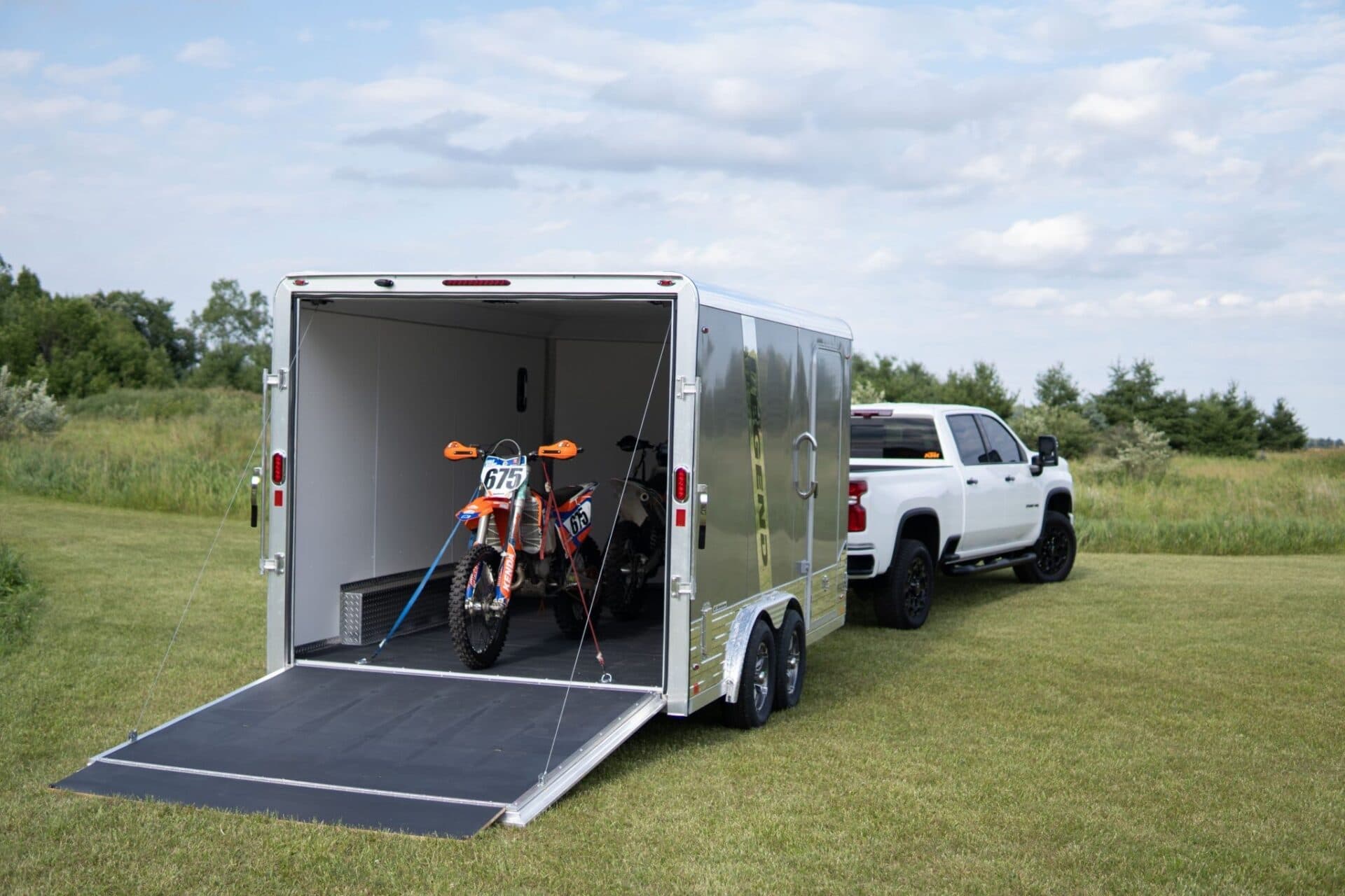 Pickup truck towing an enclosed trailer loaded with two motorcycles secured with tie-down straps
