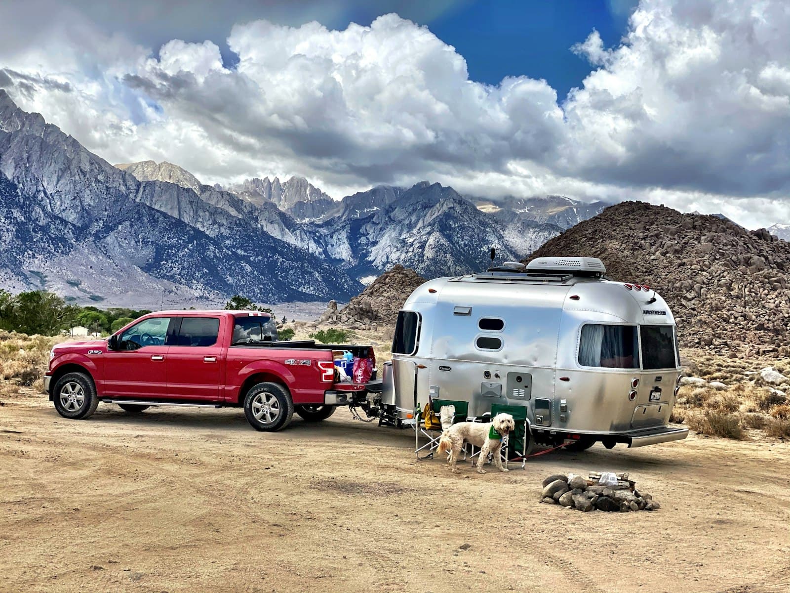 Pickup truck towing a silver travel trailer on a mountain road, illustrating tow-away RV transport
