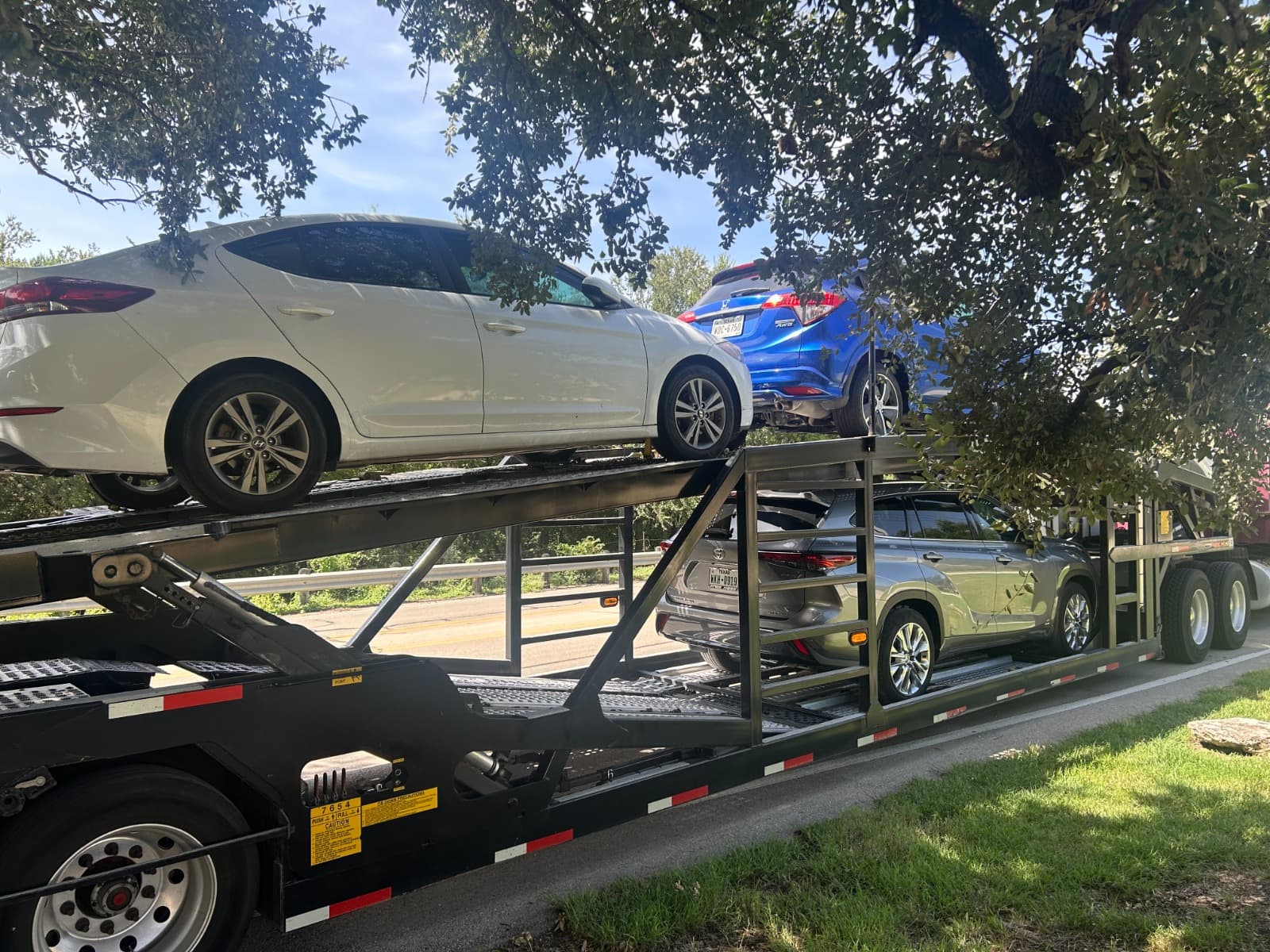 Multiple vehicles loaded on a two-level open auto transport carrier
